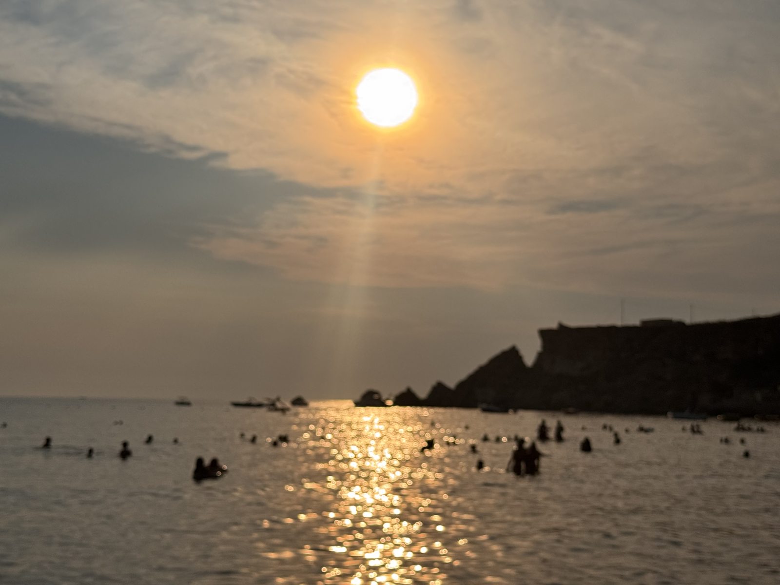 El sol cayendo sobre Golden Bay, con la gente aún en el agua