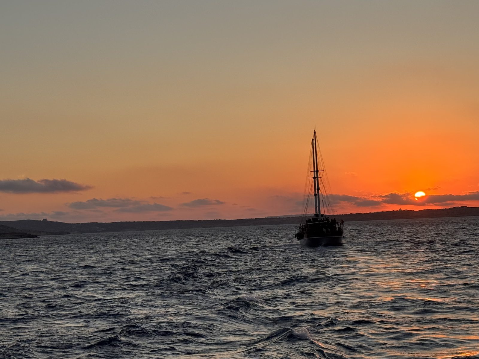 Un velero de regreso a Malta con el sol cayendo sobre el horizonte